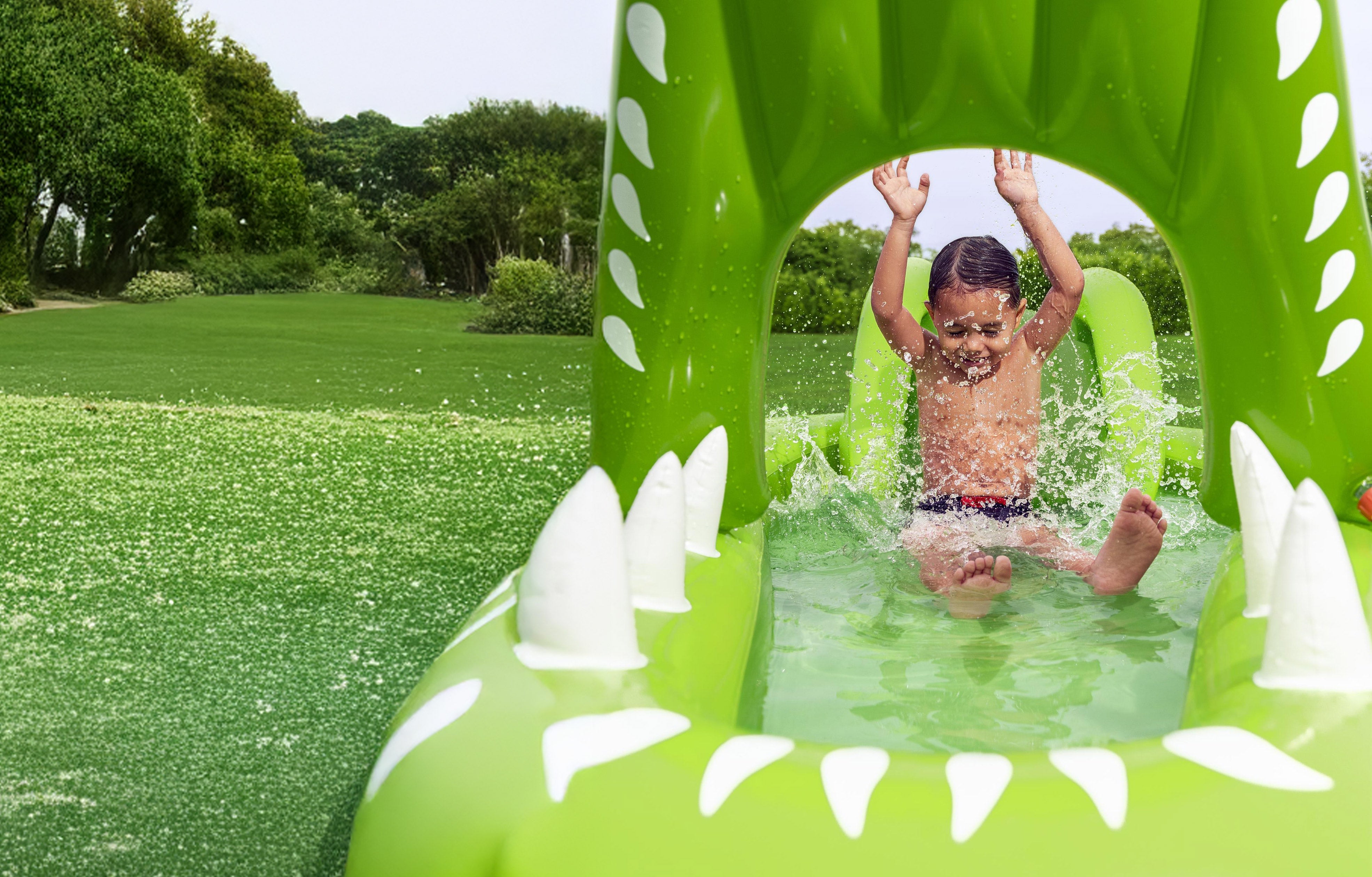 A close-up of a young boy splashing and playing in an H2OGO! Later Gator Inflatable Water Play Center & Pool.